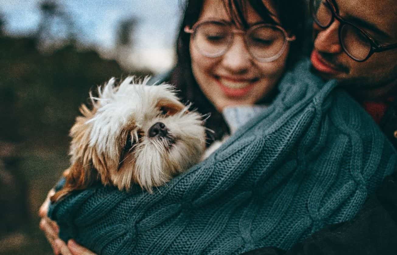 Couple holds dog Couple that wears glasses holds a dog